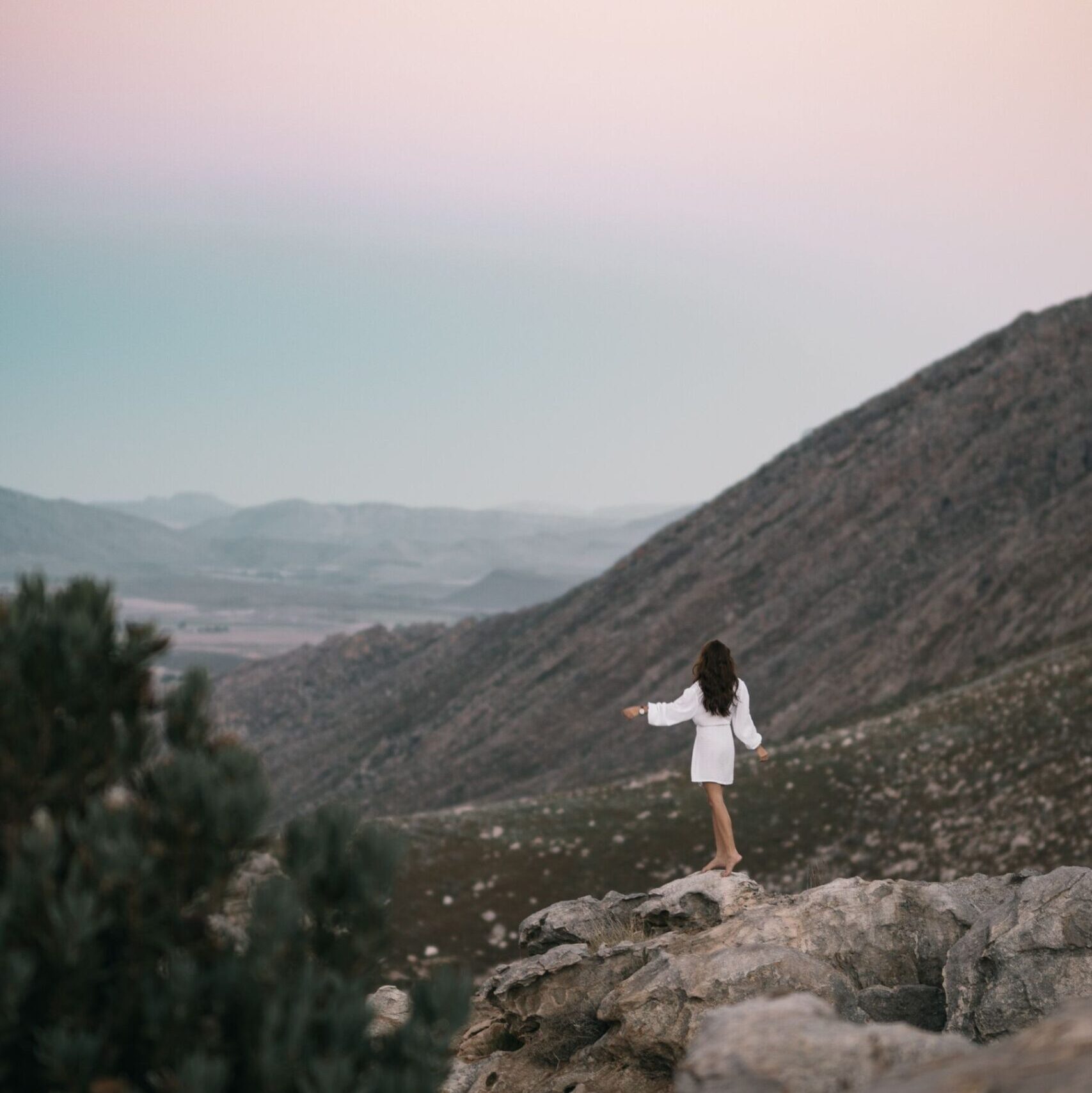Woman in mountains wearing white dress at sunset